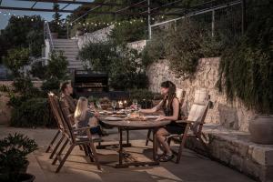 a family sitting around a table in a garden at Forest Within - Wellness Villa in Archanes in Káto Arkhánai