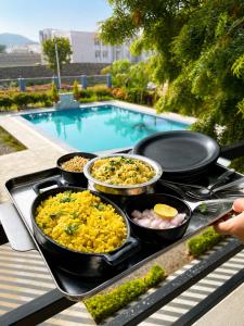 a tray of food on a table next to a pool at Atithi Farms - 4 BHK Farm Villa with Private Pool in Thūr