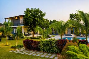 a house with a garden and a swimming pool at Atithi Farms - 4 BHK Farm Villa with Private Pool in Thūr