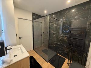 a bathroom with a shower with a glass door at La Suite Prestige in Saint-Quentin