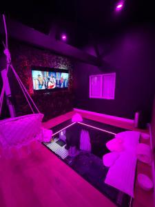 a room with a swimming pool with pink lights at La Suite Prestige in Saint-Quentin