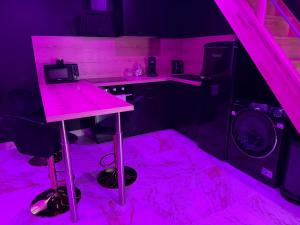 a kitchen with pink lighting and a pink table at La Suite Prestige in Saint-Quentin