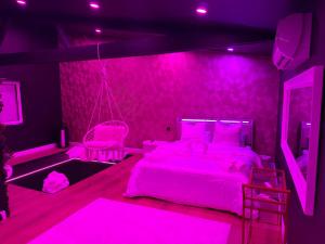 a pink bedroom with a bed with pink lighting at La Suite Prestige in Saint-Quentin +6 photos