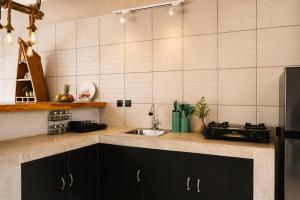 a kitchen with black cabinets and a sink at Empat Bintang Villas in Uluwatu