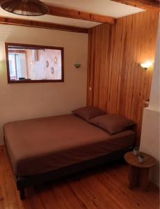 a bed in a room with wooden walls and a window at Le cocon de Barcelonnette in Barcelonnette