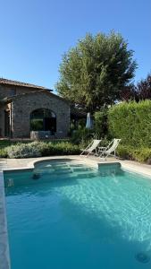 a swimming pool with two chairs and a house at Casale1918 in Pietrasanta