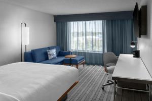 a hotel room with a bed and a blue couch at Courtyard by Marriott Flint Grand Blanc in Flint +31 photos