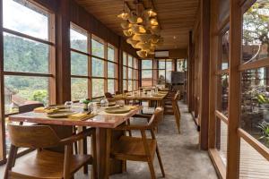 a dining room with tables and chairs and windows at Kropak Sidemen in Sidemen