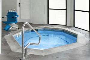 a jacuzzi tub with a chair in a bathroom at Courtyard by Marriott Flint Grand Blanc in Flint