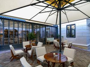 a patio with tables and chairs and an umbrella at J.K. Place Paris in Paris