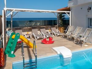 a swimming pool with a slide and chairs next to a house at Marelia Memories villa in Skaleta