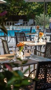 a group of tables with glasses and flowers on them at Hôtel Le Pré Galoffre in Nîmes