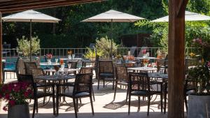 a patio with tables and chairs and umbrellas at Hôtel Le Pré Galoffre in Nîmes