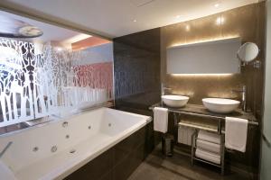 a bathroom with two sinks and a bath tub at Hotel Sancho Abarca Petit SPA in Huesca +33 photos