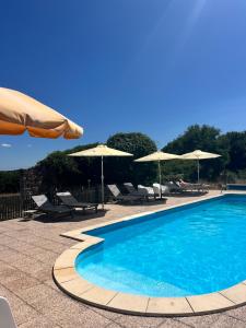 a swimming pool with chairs and umbrellas at Le Plantier2 in Beaulieu-sur-Sonnette