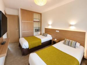 a hotel room with two beds and a flat screen tv at Alsol Los Leones Bungalows - Adults Only in Maspalomas +40 photos