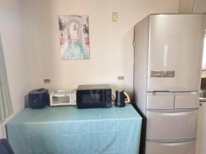 a kitchen with a microwave and a refrigerator at Sakura Inn in Chiba