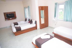 a living room with two beds and a tv at D D Luxury Inn in Chikmagalūr
