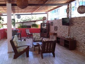 a living room with chairs and a tv on a brick wall at Swiss Flats in Porto De Galinhas