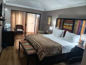a bedroom with a large bed with a blanket on it at Blyde Lodge in Graskop