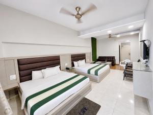 a hotel room with two beds and a television at Hotel SVD HARIDWAR in Haridwār