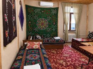 a living room with a bed and a rug at Guest House Ikathouse in Margilan