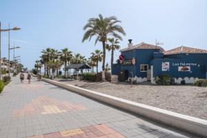 a sidewalk on the beach with palm trees and a building at Beachfront Apt Torrox Costa in Torrox