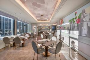 a restaurant with tables and chairs and a wall of windows at Mercure Kunming Wujiaba in Kunming