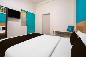 a bedroom with a white bed with a blue accent at Collection O near Tunjungan Plaza formerly K15 in Kedongdong