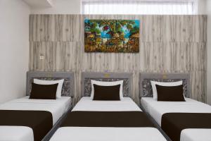 a room with two beds and a painting on the wall at Collection O near Tunjungan Plaza formerly K15 in Kedongdong
