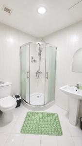 a bathroom with a shower and a toilet and a green rug at Guest House Ikathouse in Margilan