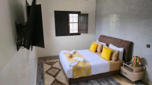 a bedroom with a bed with yellow pillows and a television at Le Paisible Atlas in Marrakesh +19 photos