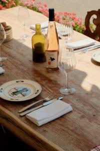 a wooden table with a bottle of wine and glasses at Hôtel Arnold in Itterswiller