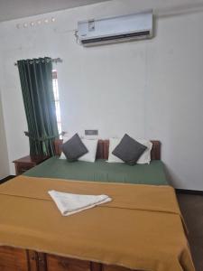 a bedroom with a bed with a green blanket and a window at KRISHNASHILa in Varkala