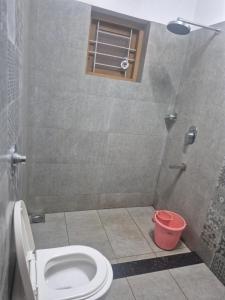 a bathroom with a toilet and a shower with a window at KRISHNASHILa in Varkala