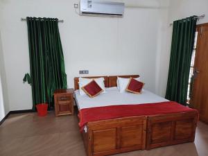 a bedroom with a large bed with green curtains at KRISHNASHILa in Varkala