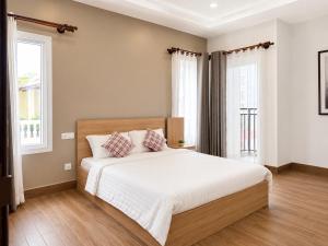 a bedroom with a bed with white sheets and two windows at Sopor Resident in Phnom Penh