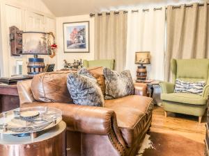 a living room with a leather couch and two chairs at A Charming Nature Retreat in Greensboro