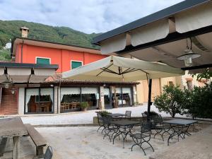 a patio with tables and chairs and an umbrella at Agriturismo Vigneto Vecio in Valdobbiadene