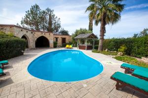 a swimming pool in a yard with benches and a building at Villa Olive Grove 3 in Paphos +8 photos