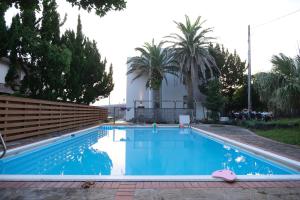 a swimming pool with blue water and palm trees at Villa aco's in Ako