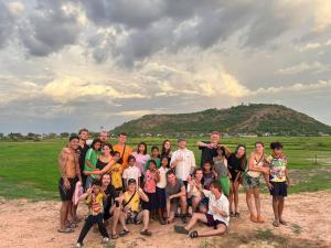 a group of people posing for a picture in front of a hill at The Funky Village in Siem Reap