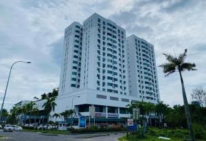 a tall white building with a palm tree in front of it at Likas Square - KK Apartment Suite in Kota Kinabalu