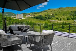a patio with chairs and tables and an umbrella at Sunken Tsaghkadzor in Tsaghkadzor
