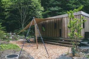 a tent in front of a wooden building at Earthboat Ueda Onsen in Nagano
