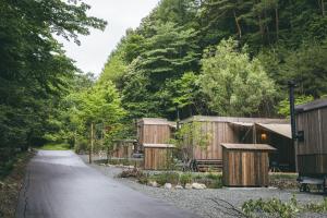 a gravel road with wooden buildings and trees at Earthboat Ueda Onsen in Nagano +38 photos