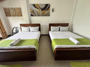 a bedroom with two beds with green sheets at Prabhaz grand villa in Hatton