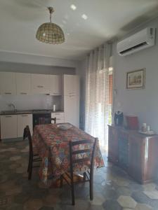 a dining room with a table and a kitchen at Holiday house daviale in Schisò
