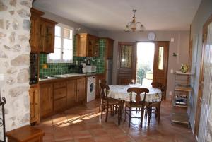 a kitchen with a table and chairs and a kitchen with green tiles at Bergerie de la buèges in Saint-André-de-Buèges