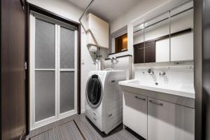 a bathroom with a washing machine and a sink at The Shelbourne Furano in Furano